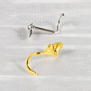Detail of gold and silver S-shaped nose studs with butterfly and fan-shaped accents