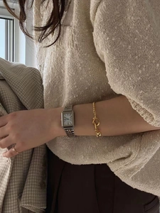 Elegant rectangular silver watch paired with a golden knot bracelet on a model wrist