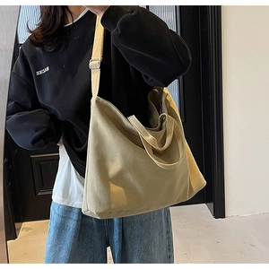 Detail of adjustable metal buckle and canvas shoulder strap on a khaki tote bag