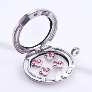 Open silver glass locket showing four red polka dot mushroom charms inside detail