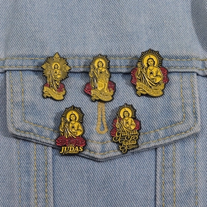 Detail of five gold San Judas Tadeo enamel pins pinned on a blue denim jacket pocket