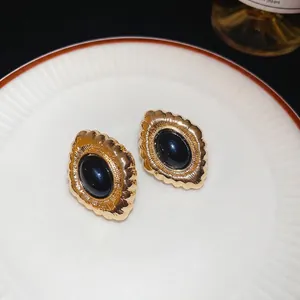Elegant vintage oval stud earrings with black stone and gold-toned scallop edges