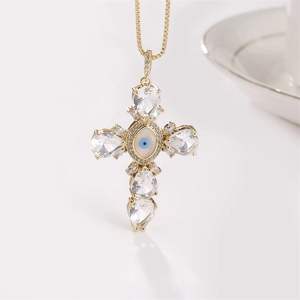 Gold necklace with teardrop zircon cross pendant and evil eye center on beige background