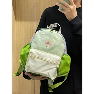 Close-up of color-block backpack in green and beige with WanWanle round label detail