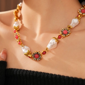 Macro shot of vintage necklace featuring irregular pearls, red gems and floral rhinestones