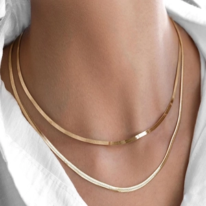 Vintage gouden slangenketting halskettingen gelaagd gedragen op een wit overhemd