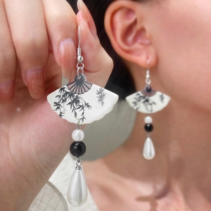 Detail of fan-shaped drop earrings with bamboo ink patterns and white pearl beads