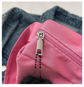 Gros plan sur la fermeture éclair argentée fluide d'un sac bandoulière en nylon rose fuchsia