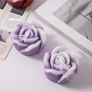 Detail of rose-shaped scented candles with purple gradient finish and ribbon decor