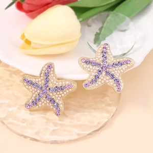 Boucles d'oreilles étoile de mer avec strass violets et perles sur plateau