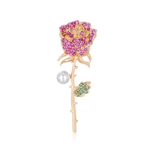 Close-up of pink rhinestone rose brooch with gold stem, pearl accent and green leaves
