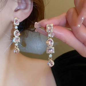 Macro shot of pink crystal geometric earrings with sparkling diamonds and long tassels