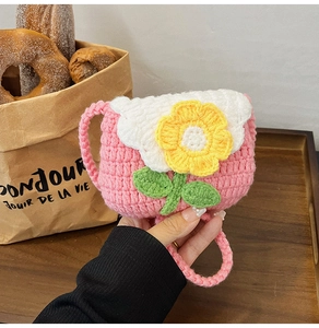 Close-up of handmade crochet bag featuring 3D floral accents and a woven shoulder strap