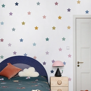 Colorful star wall decals scattered over a bed headboard in a cozy girl bedroom