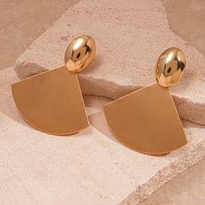 Close-up of golden geometric fan-shaped earrings with brushed metal texture and oval studs
