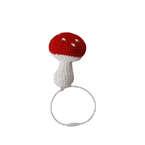 Handmade crochet red mushroom keychain with white spots on a minimalist white background