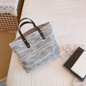 Détail du sac cabas en tissu tissé avec poignée en cuir noir et rivets dorés