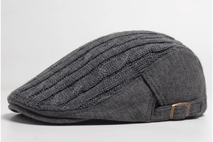 Detail of grey knitted flat cap with cable stitch pattern and metal side buckle