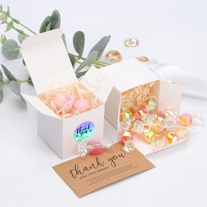 Detailed view of a white cube paper gift box with a thank you card and candy setup
