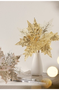 Detail of golden glitter artificial poinsettia flower in white vase for Christmas decor