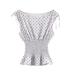 Detail of white polka dot top with elastic smocking waist and ruffled hemline