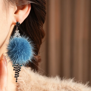 Macro detail of blue fur ball earrings with diamond tassels for winter style