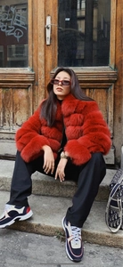 Close-up of bright red faux fur jacket showing horizontal segmented texture and plush fur