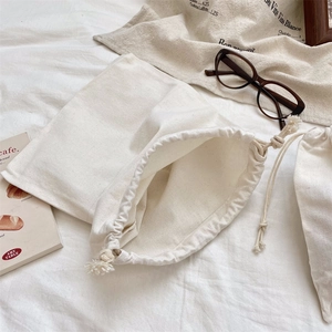 Vue détaillée d'une pochette de rangement en coton blanc cassé avec cordon serrage