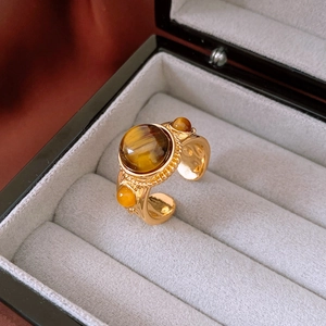 Vista macro di un anello d'oro vintage con pietra occhio di tigre su scatola di velluto grigio