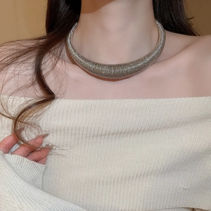 Close-up of silver textured metal collar necklace with fine horizontal thread details