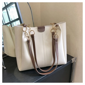 Detail of off-white PU leather tote bag with brown straps and golden metal rings