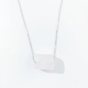 Close-up of a silver chain necklace with a translucent rectangular natural stone pendant