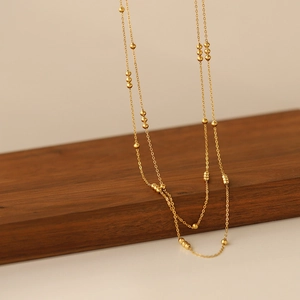 Detail of gold-plated titanium steel chain with spherical beads on wooden stand