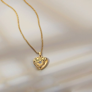 Detailed shot of a heart locket pendant with filigree patterns and a center zircon stone