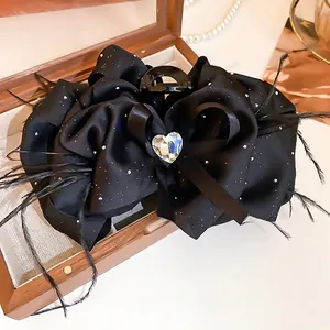 Black satin bow hair claw with sparkling glitter, feather detail and heart rhinestone