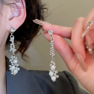Detail view of rhinestone floral pearl drop earrings worn by a model for an elegant look