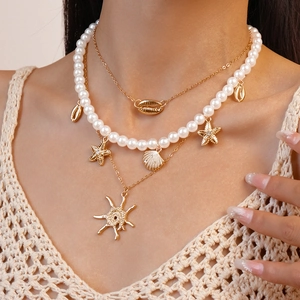 Detail of bohemian layered necklace with gold shells, starfish and pearl accents