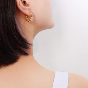 Fashionable 18K gold plated titanium steel beaded hoop earrings worn by a model
