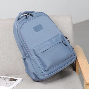 Blue nylon school backpack with multi-pocket design on a minimalist fabric sofa chair