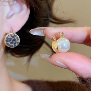 Detail of leopard print C-shaped hoop earrings with gold trim and pearl embellishment