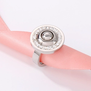 Detailed macro view of a silver stainless steel ring with zircon inlay on a pink ribbon