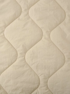 Macro shot of wave quilted beige fabric with fine stitching for retro jacket texture