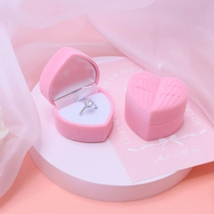 Pink heart-shaped velvet jewelry box with wing relief featuring a silver diamond ring detail