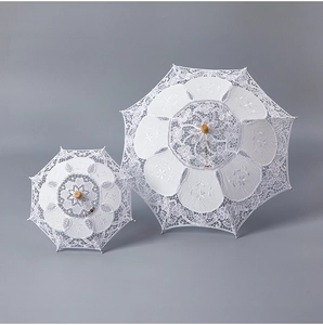 Top view of white lace wedding umbrellas with intricate floral embroidery and wooden handle