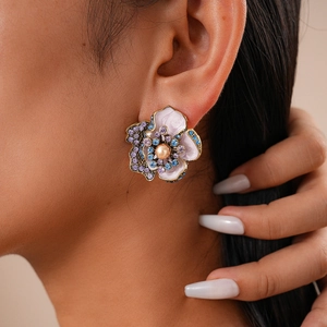 Détail de boucles d'oreilles fleur rose avec perle et cristaux portées par un mannequin