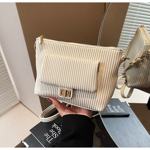 Detail of cream corduroy shoulder bag with gold twist lock and fine leather strap
