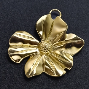 Macro shot of a golden stainless steel flower pendant with textured petals and ring