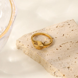 Bague soleil empilable plaquée or 18 carats présentée sur un support en pierre naturelle