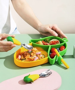Macro detail of the corn-shaped silicone baby plate with matching spoon and fork set