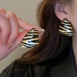 Detail shot of vintage geometric triangle earrings in gold and black striped pattern